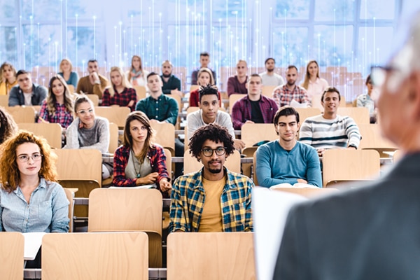 A classroom scenario where a professor is giving lecture to his students sitting infront of him.