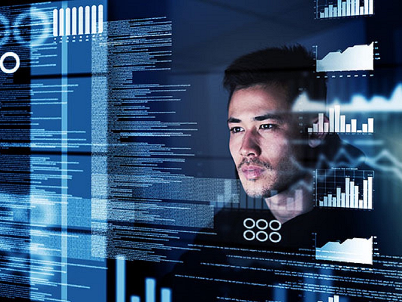 Man looking at a screen intently with graphs and text