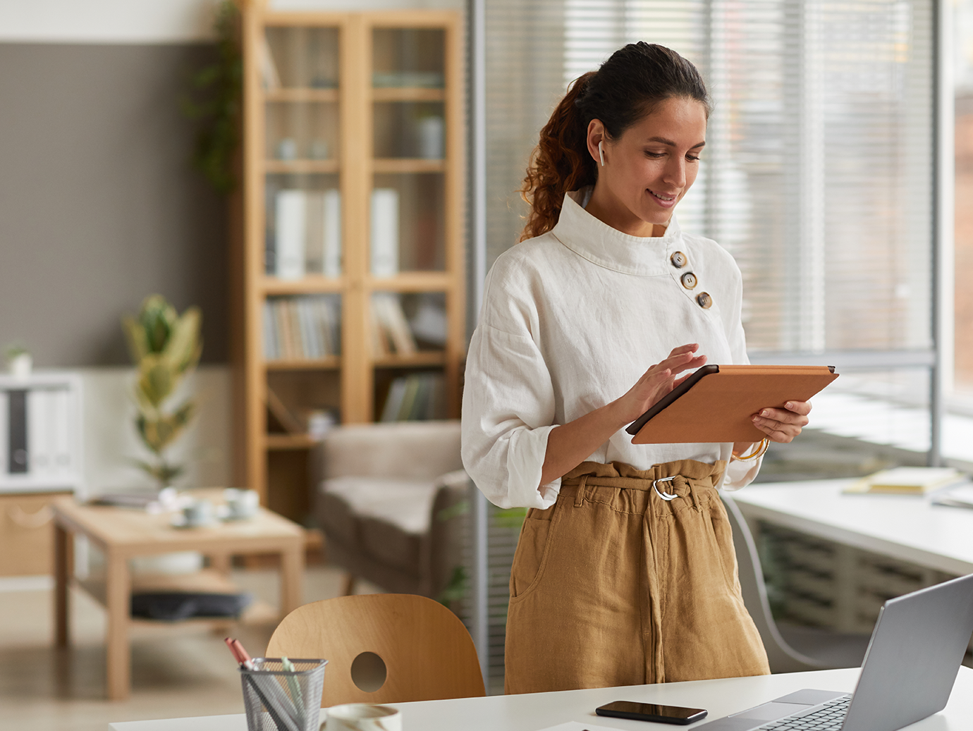 A lady is happy as she looks at the tablet in her living room