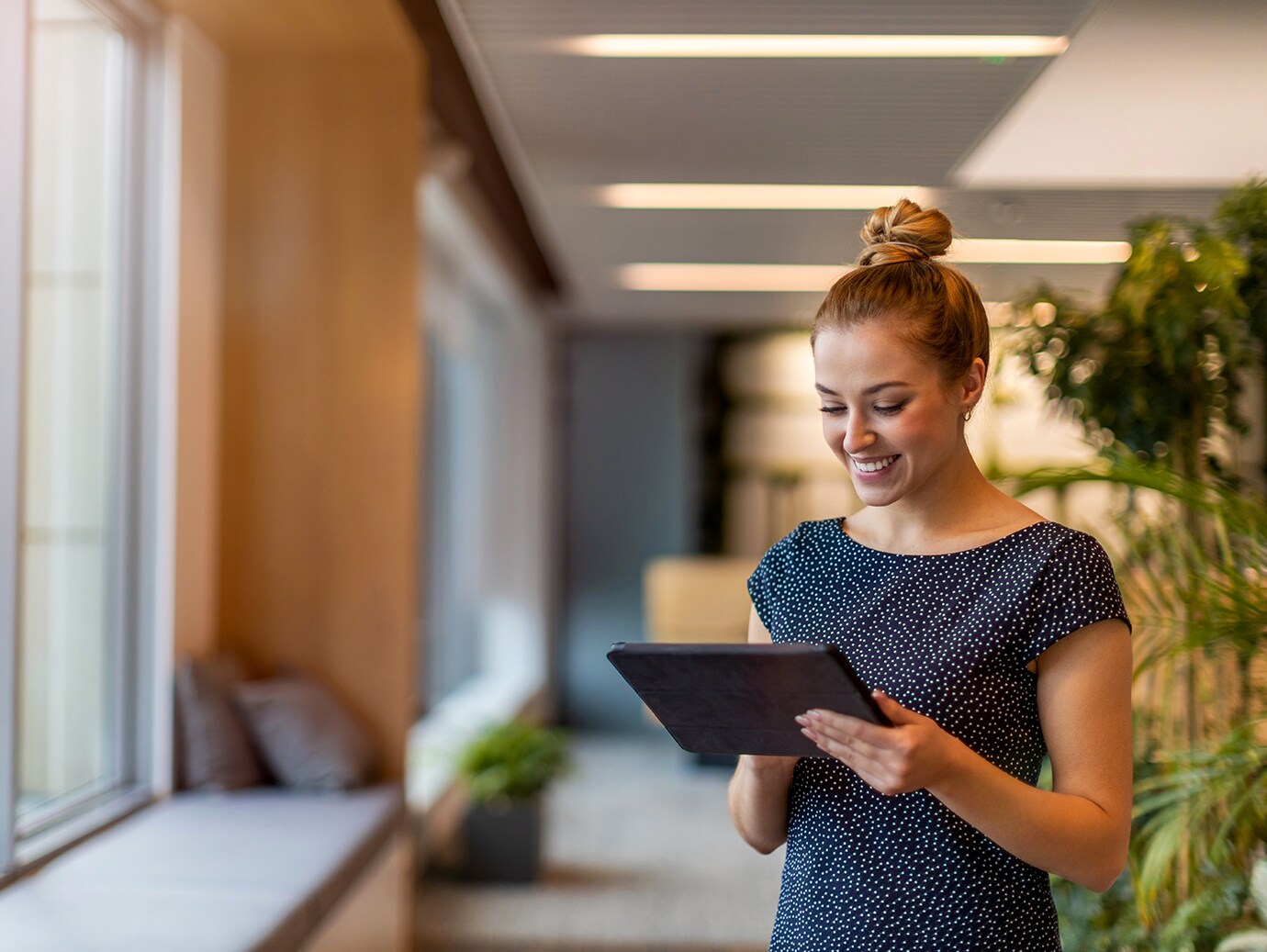 A woman looking down at a tablet she's holding in an office