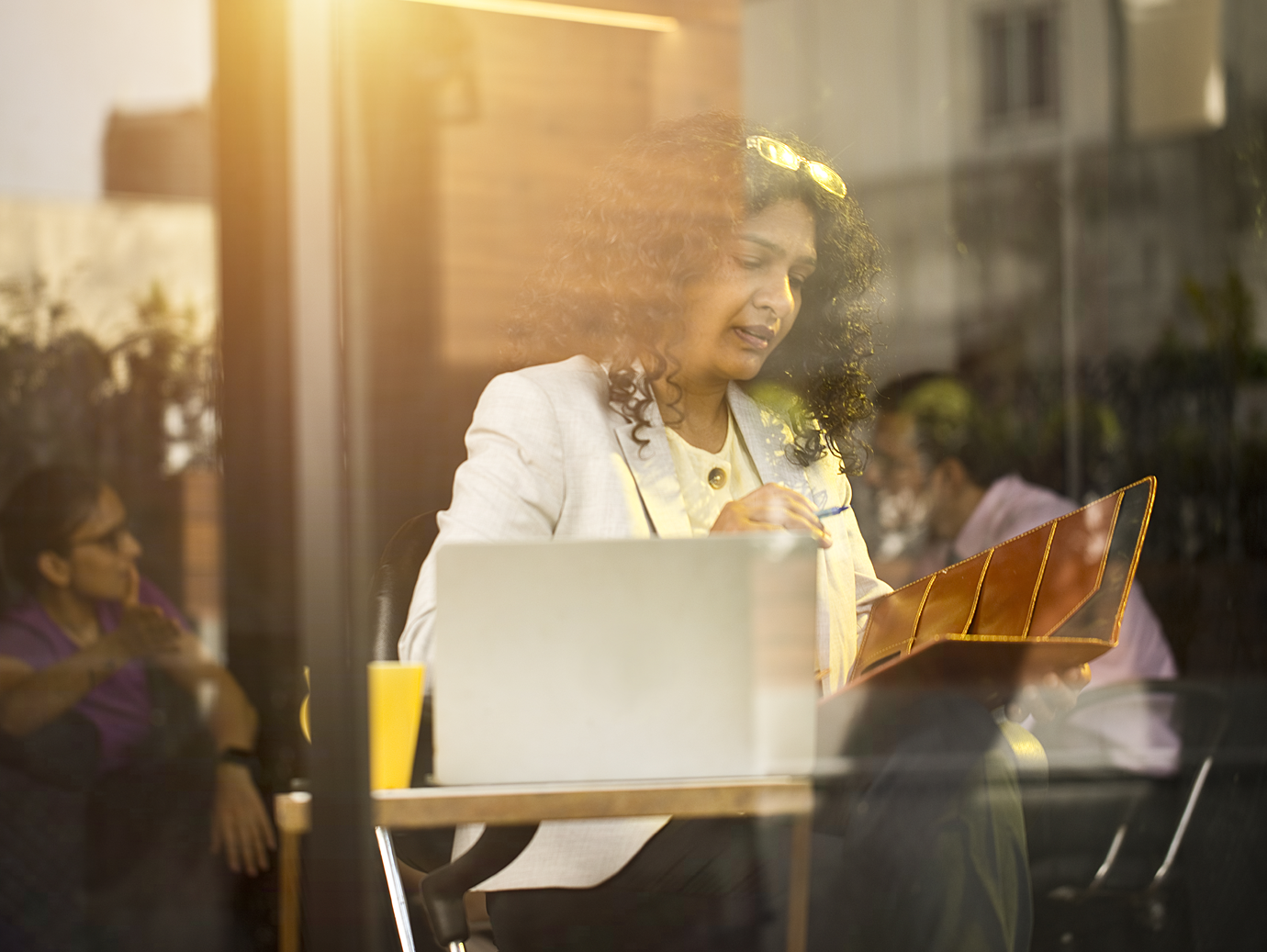 Woman sitting at a table, looking at a leather file in a cafe