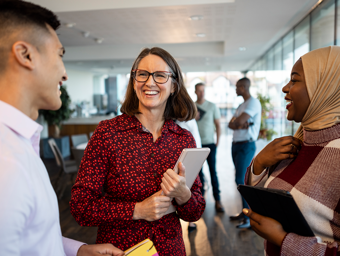 Three colleagues in conversation in an office lobby