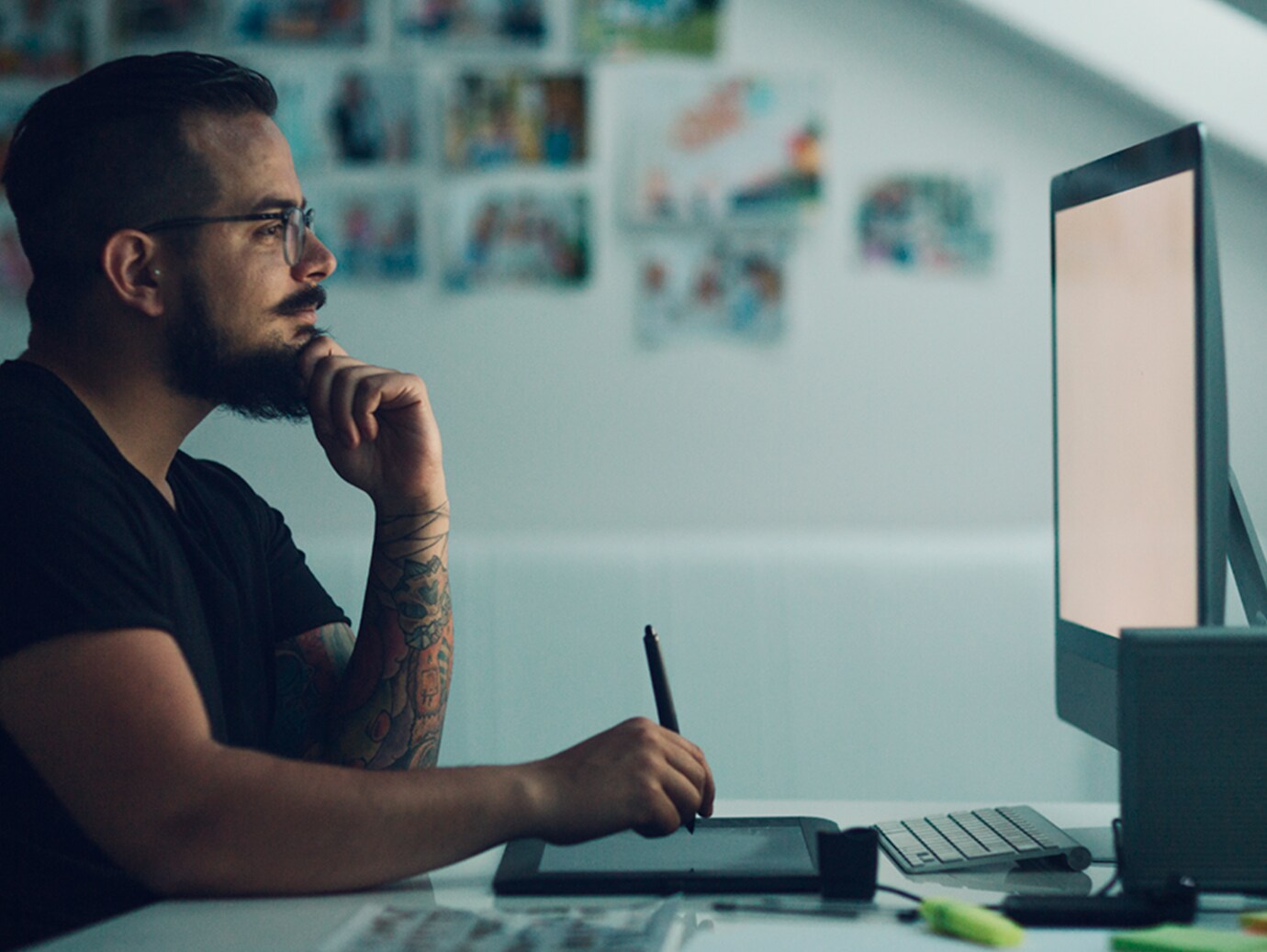 A man noting down notes looking at a desktop screen