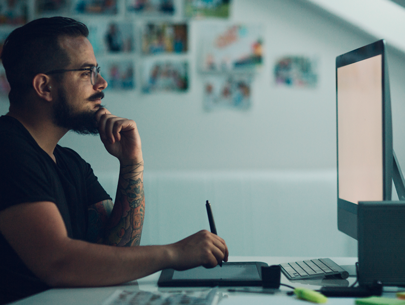 A man noting down notes looking at a desktop screen