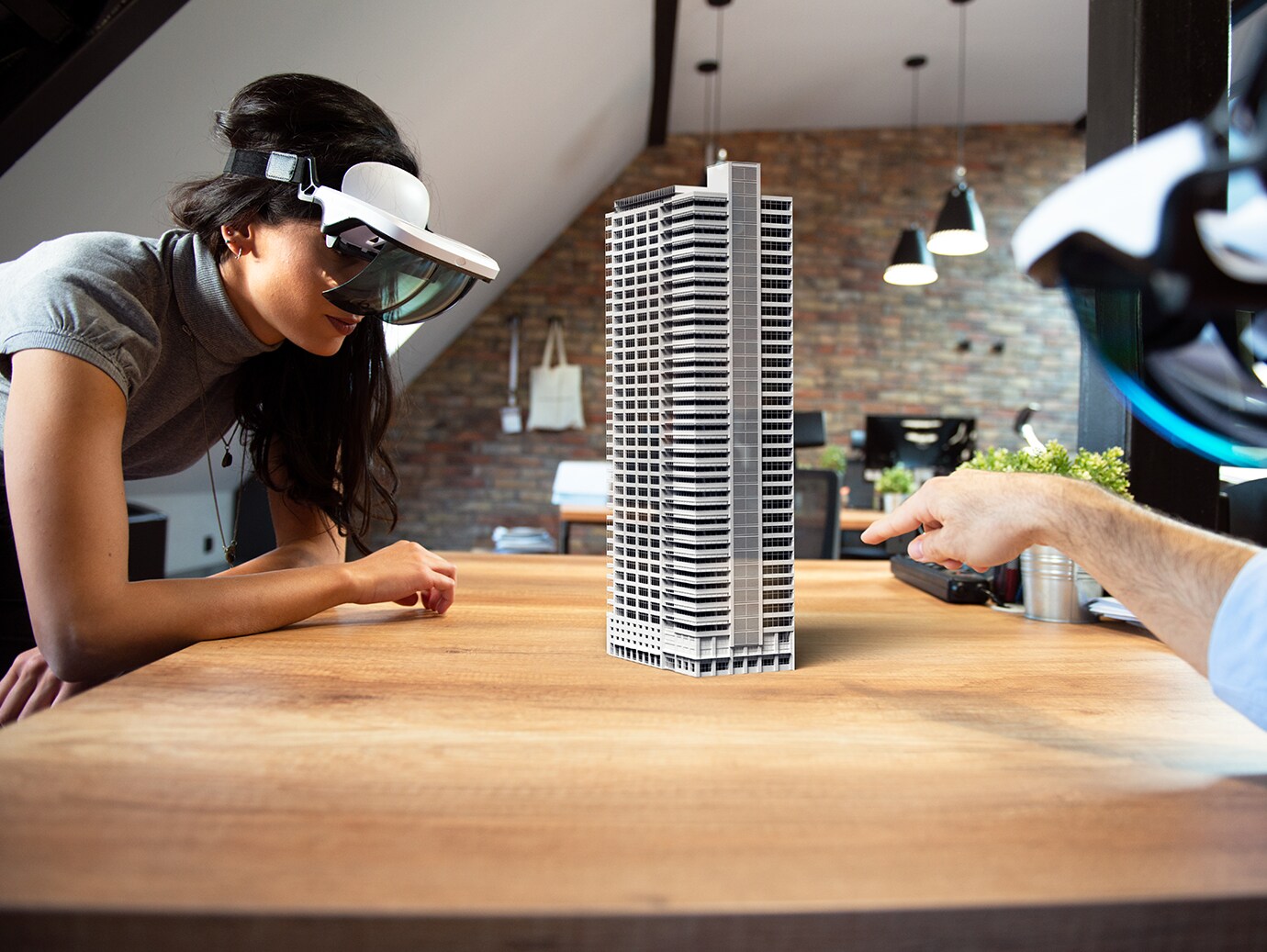 Two people wearing smart glasses, looking at a model of a tower on a table