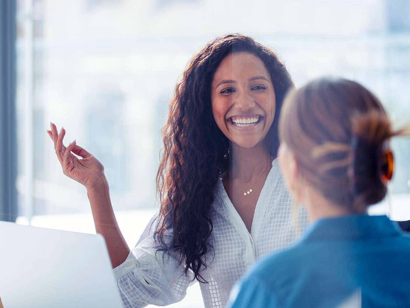 Woman in conversation, smiling at another woman