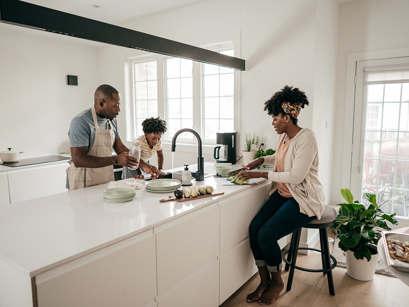 A family of three doing chores around a kitchen island