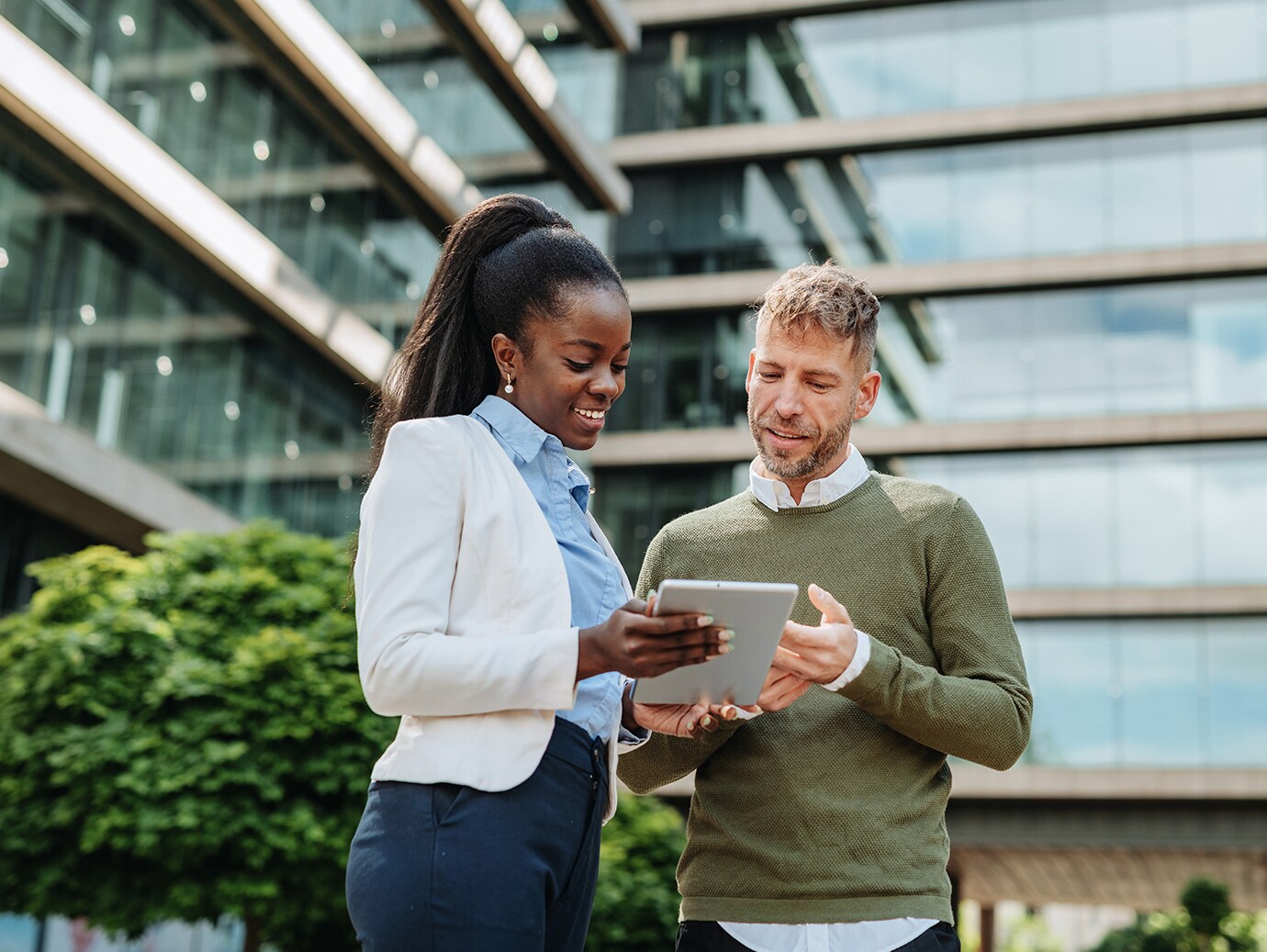 A woman holding a tablet having a conversation with a man