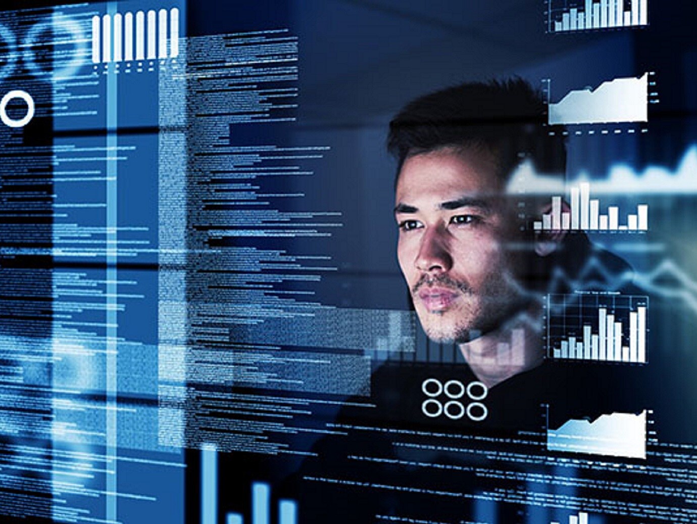 Man looking at a screen intently with graphs and text