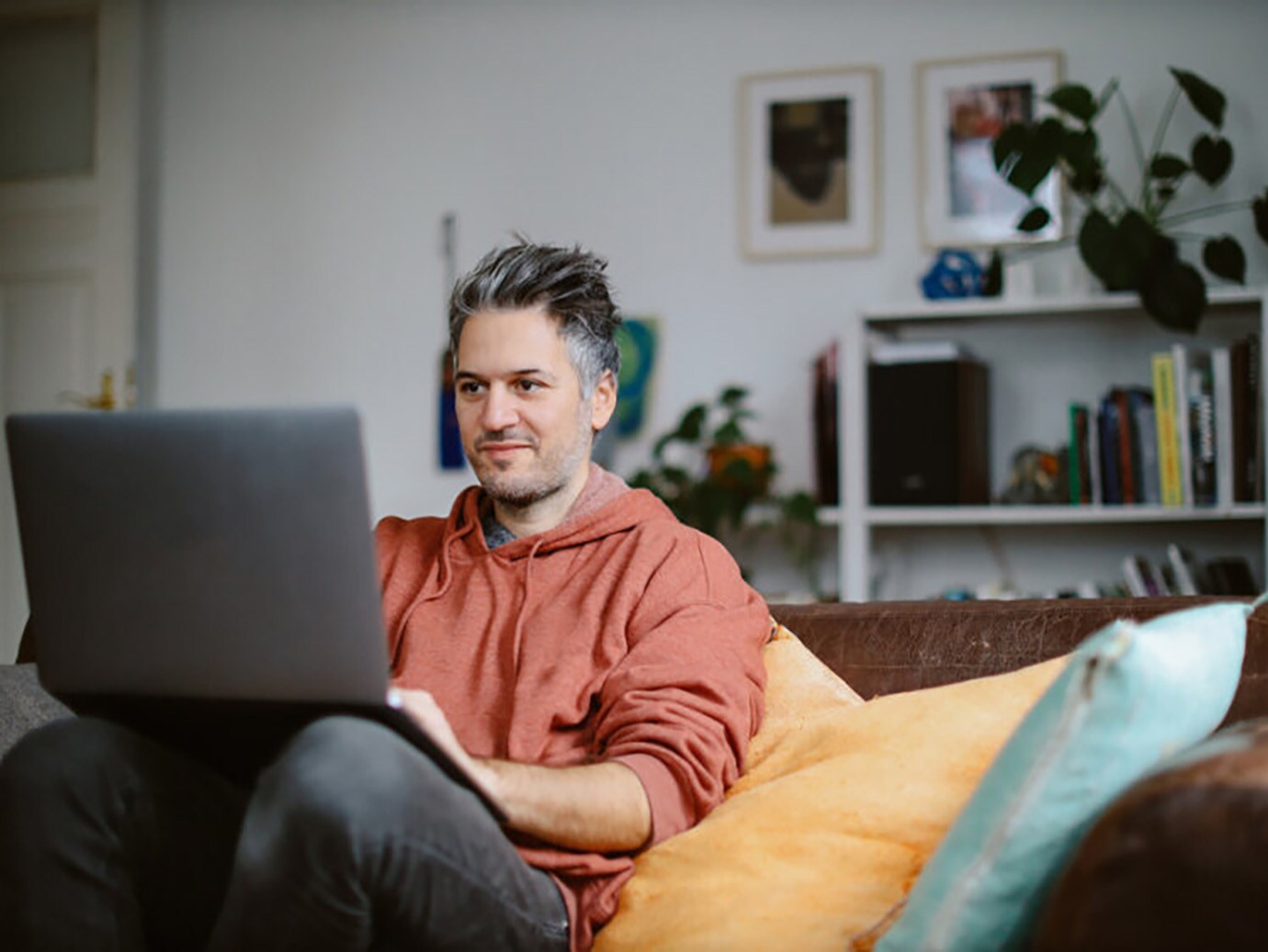 Man working with a laptop in his lap, sitting on a sofa