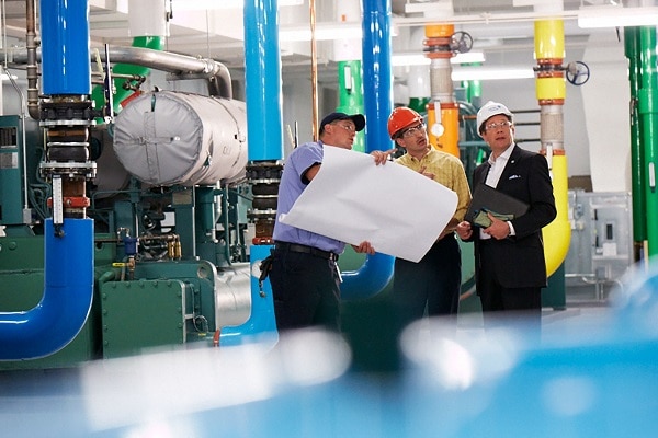 A higher official with two employees inspecting with a blueprint in hands