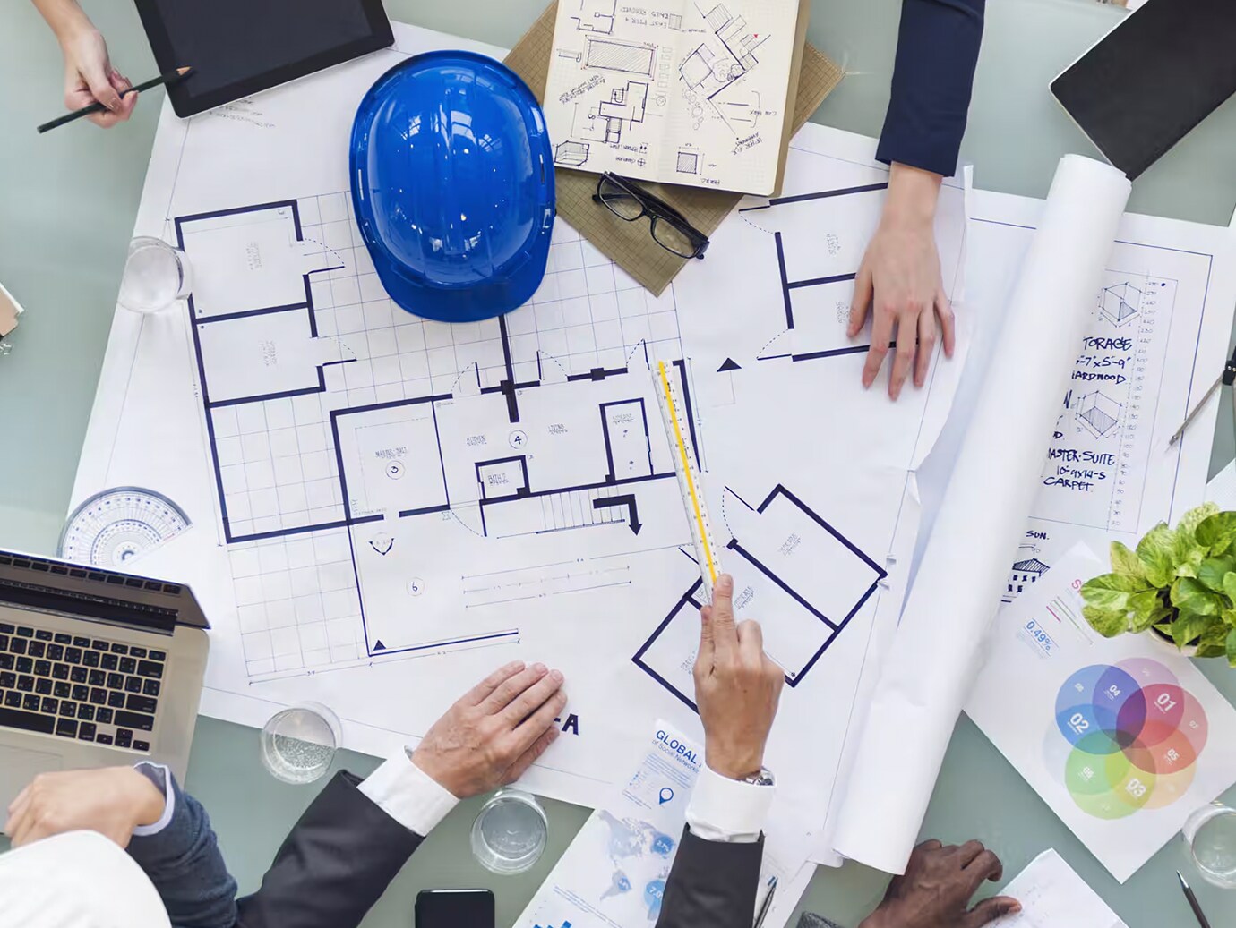 Top view of people having a discussion around a conference table with a floor plan on it