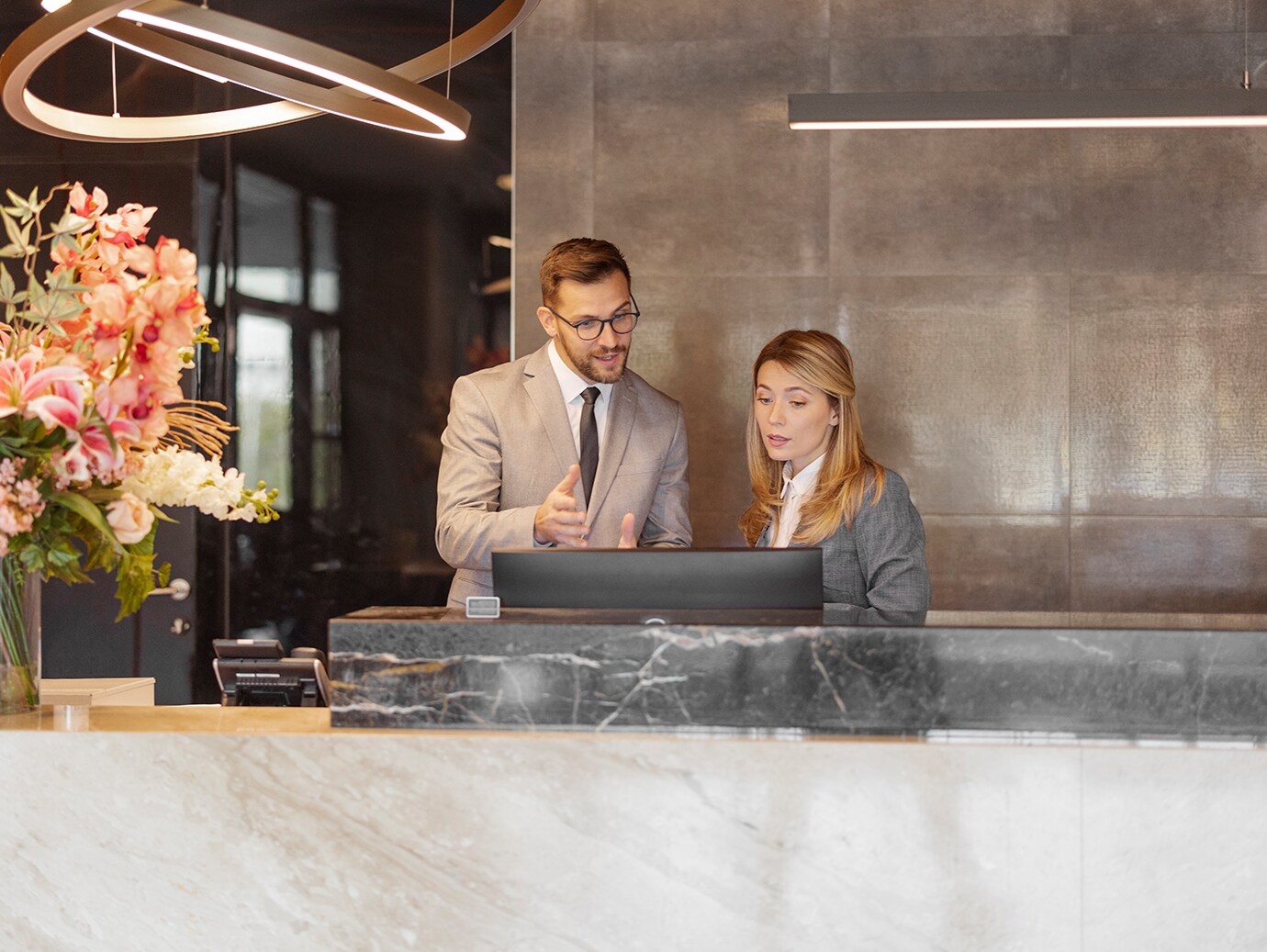 Two hotel staff having a conversation behind the reception desk