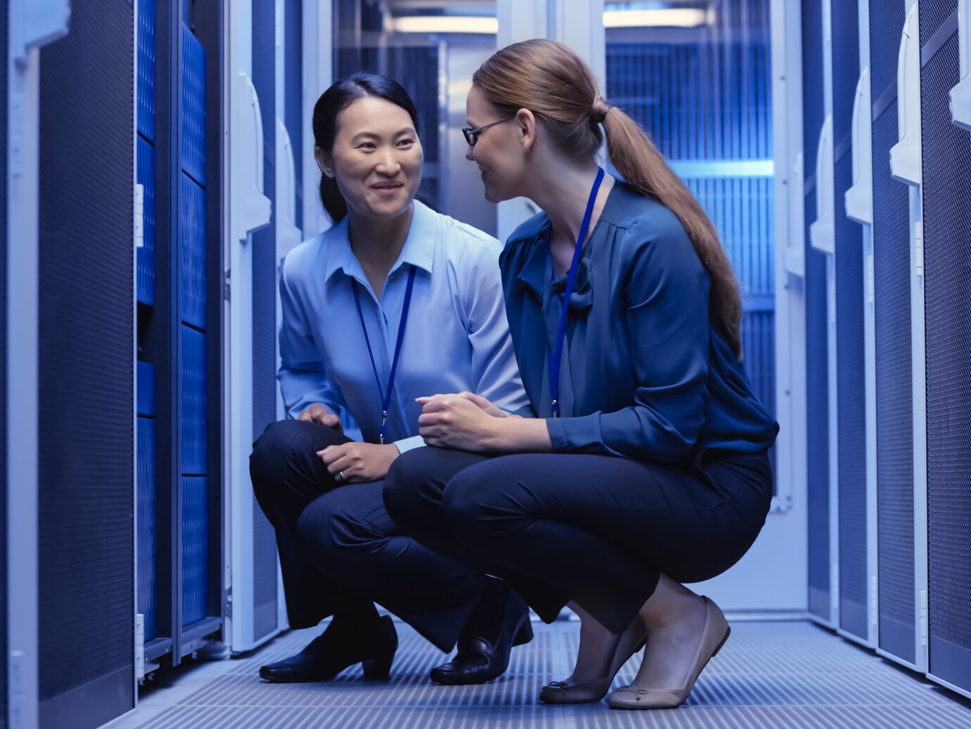 Two women in conversation in front of a data server rack