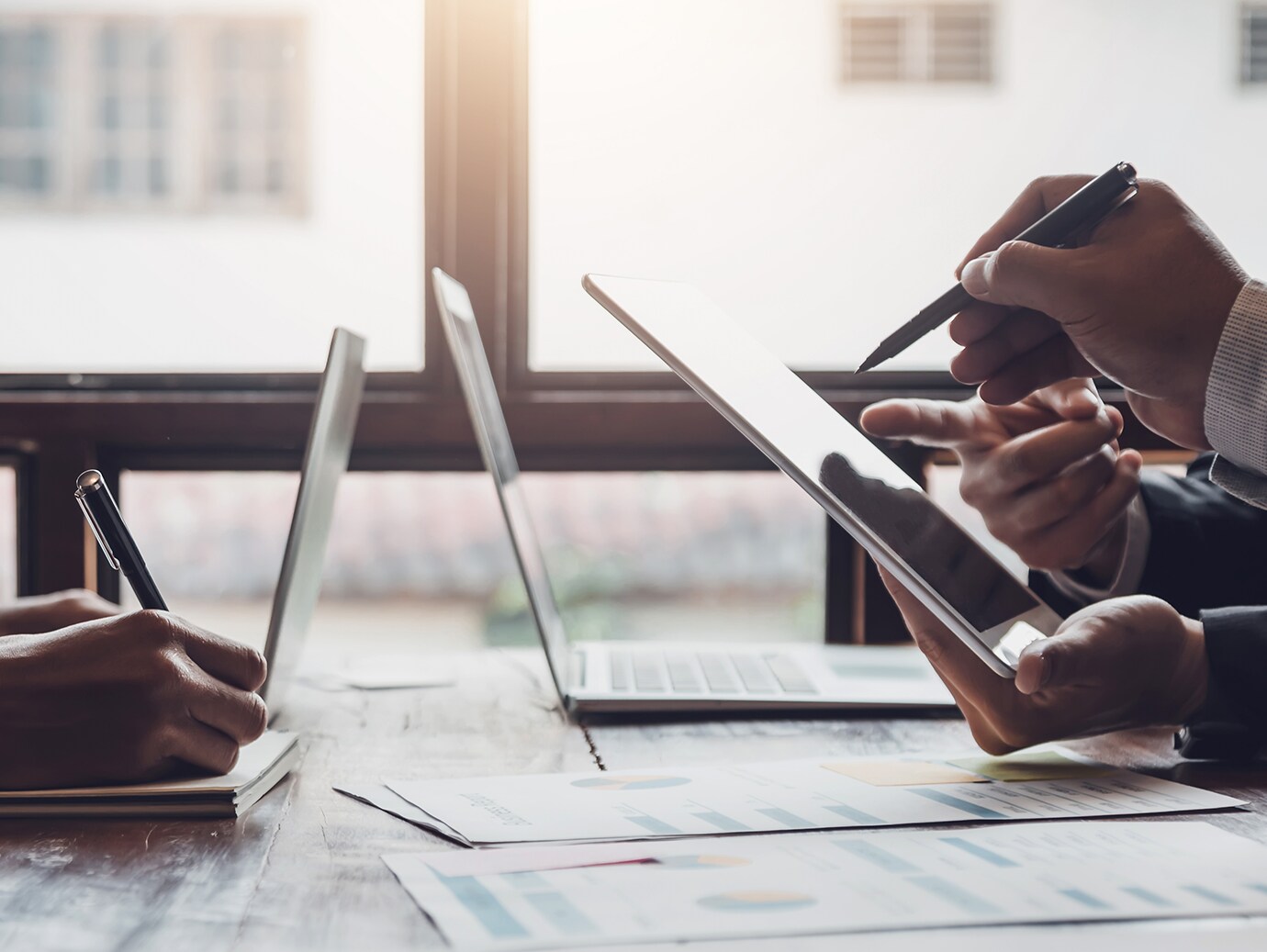 Close-up on a conference table with laptops and hands of people working