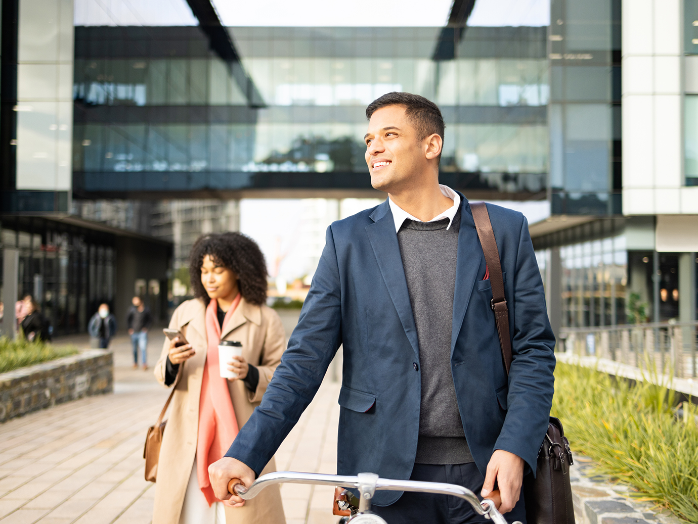 Man in formal attire walking with his bicycle in a corporate office campus