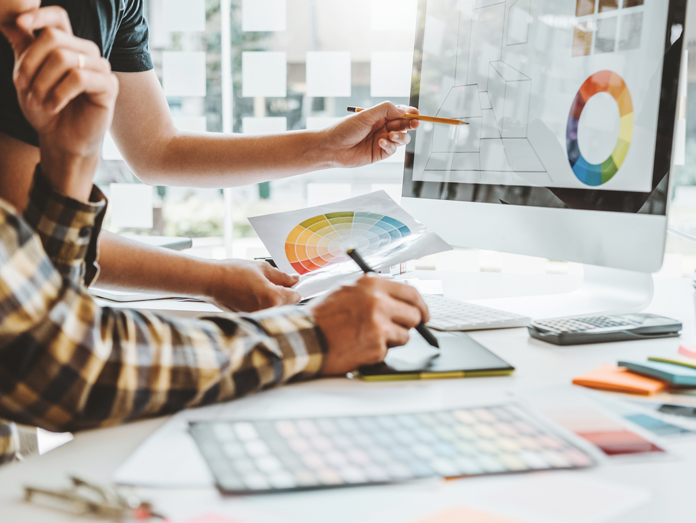 Two colleagues in discussion in front of a computer, while one points at the screen