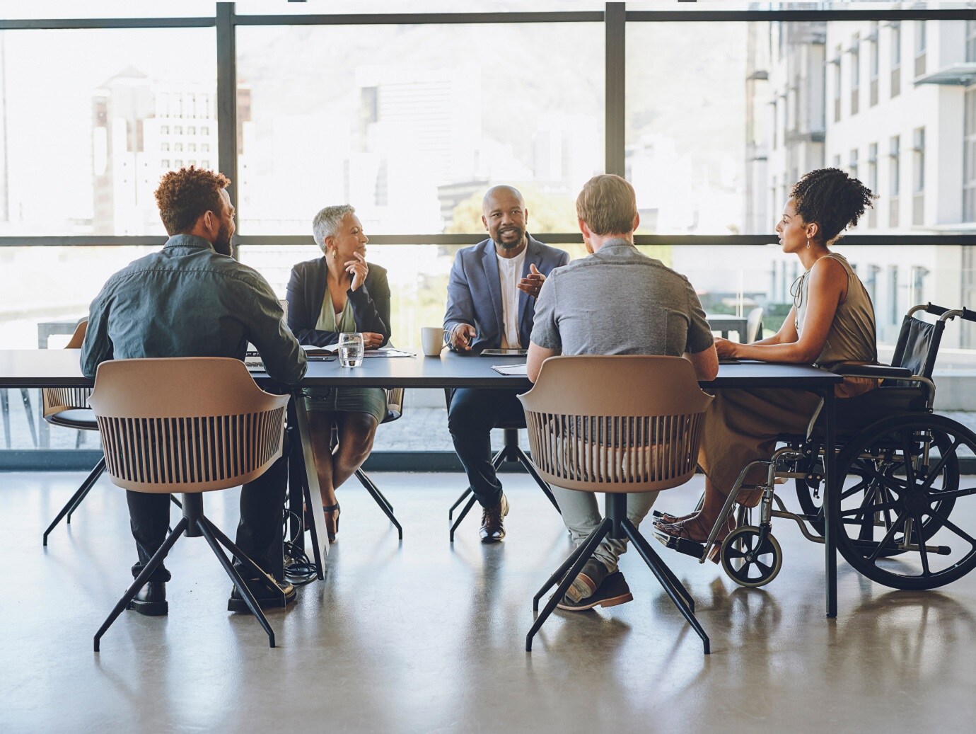 A group of people with one on wheelchair discussing around a table