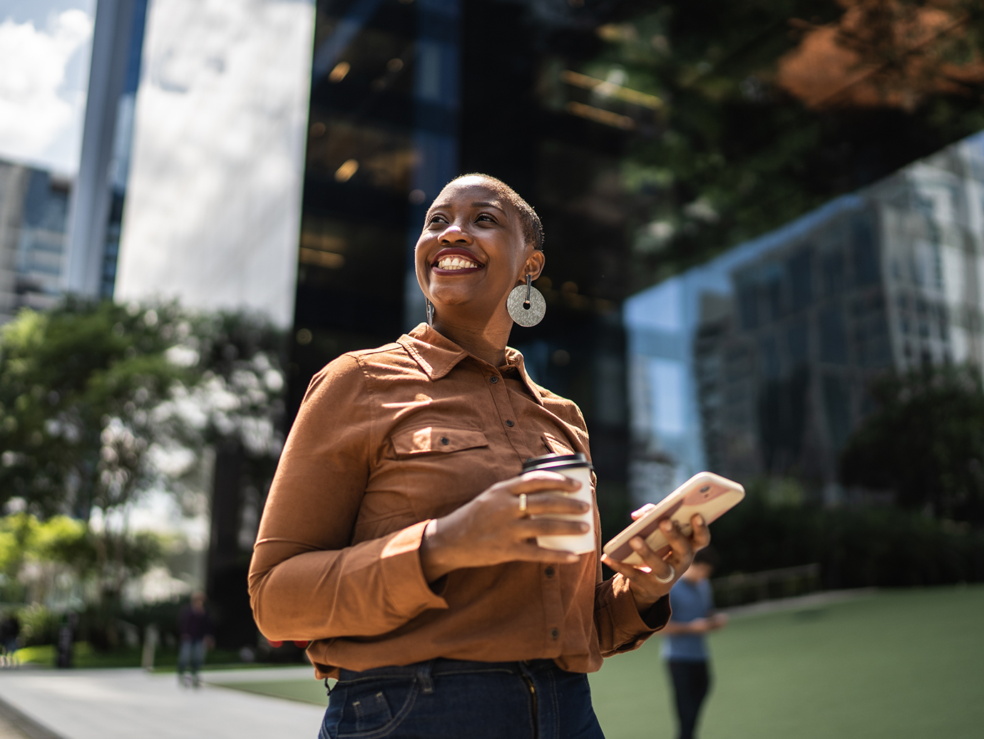Woman smiling holding a coffee glass and her phone