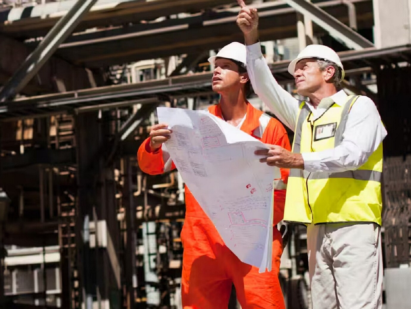 Two employees inspecting at a site with a blueprint in hand