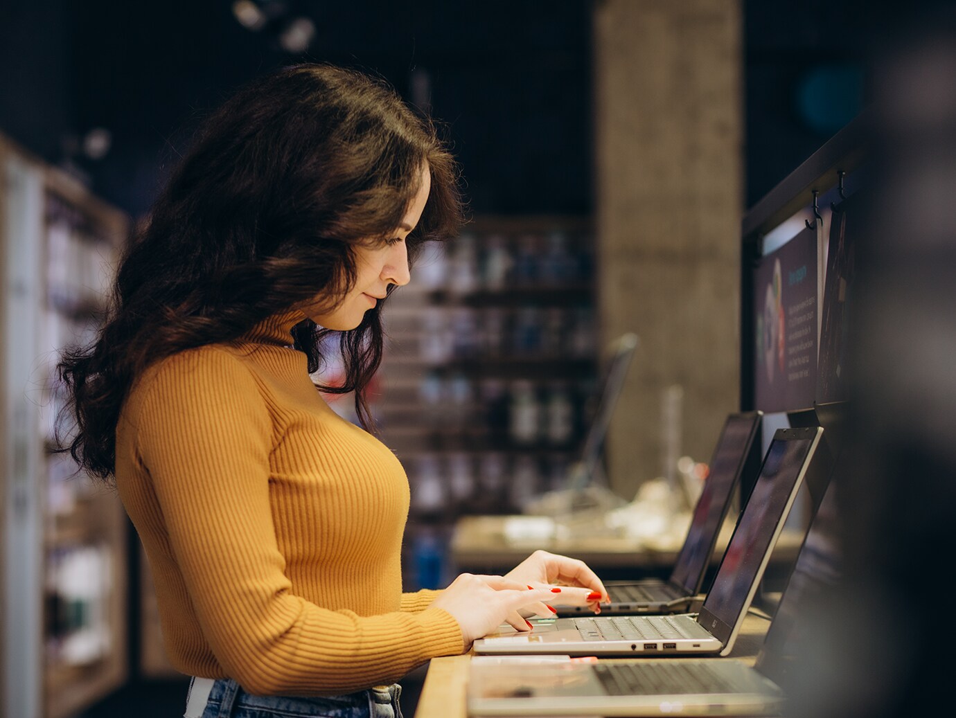 Side view of a woman trying a laptop in an electronics  store