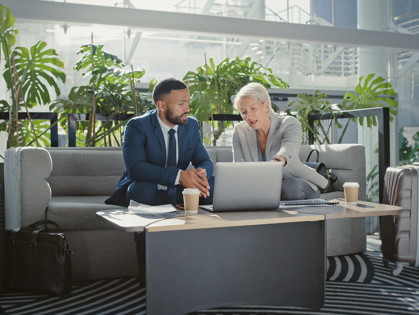 An elderly woman speaking to a man in formal attire sitting on a sofa