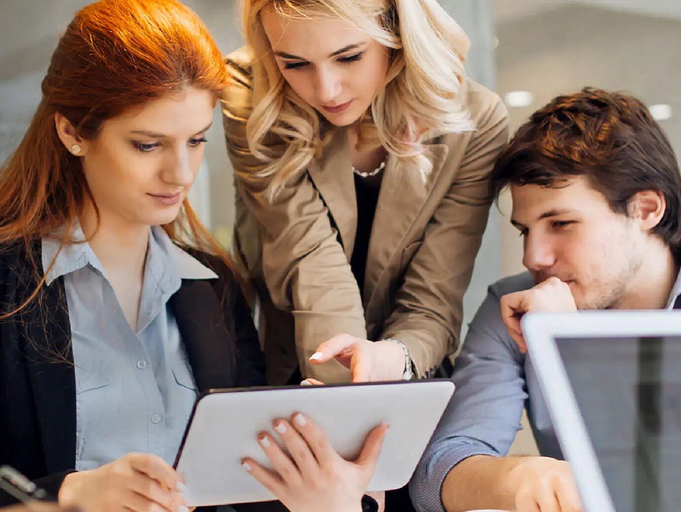 Three employees looking at a tablet PC