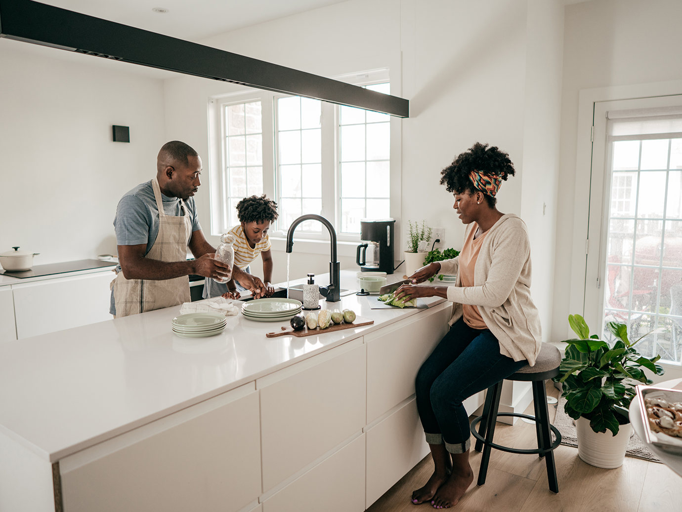 A family of three doing chores around a kitchen island