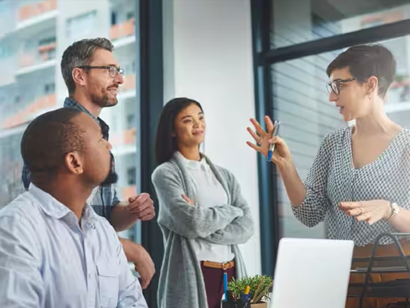 Three people listening intently to a woman talking in an office room